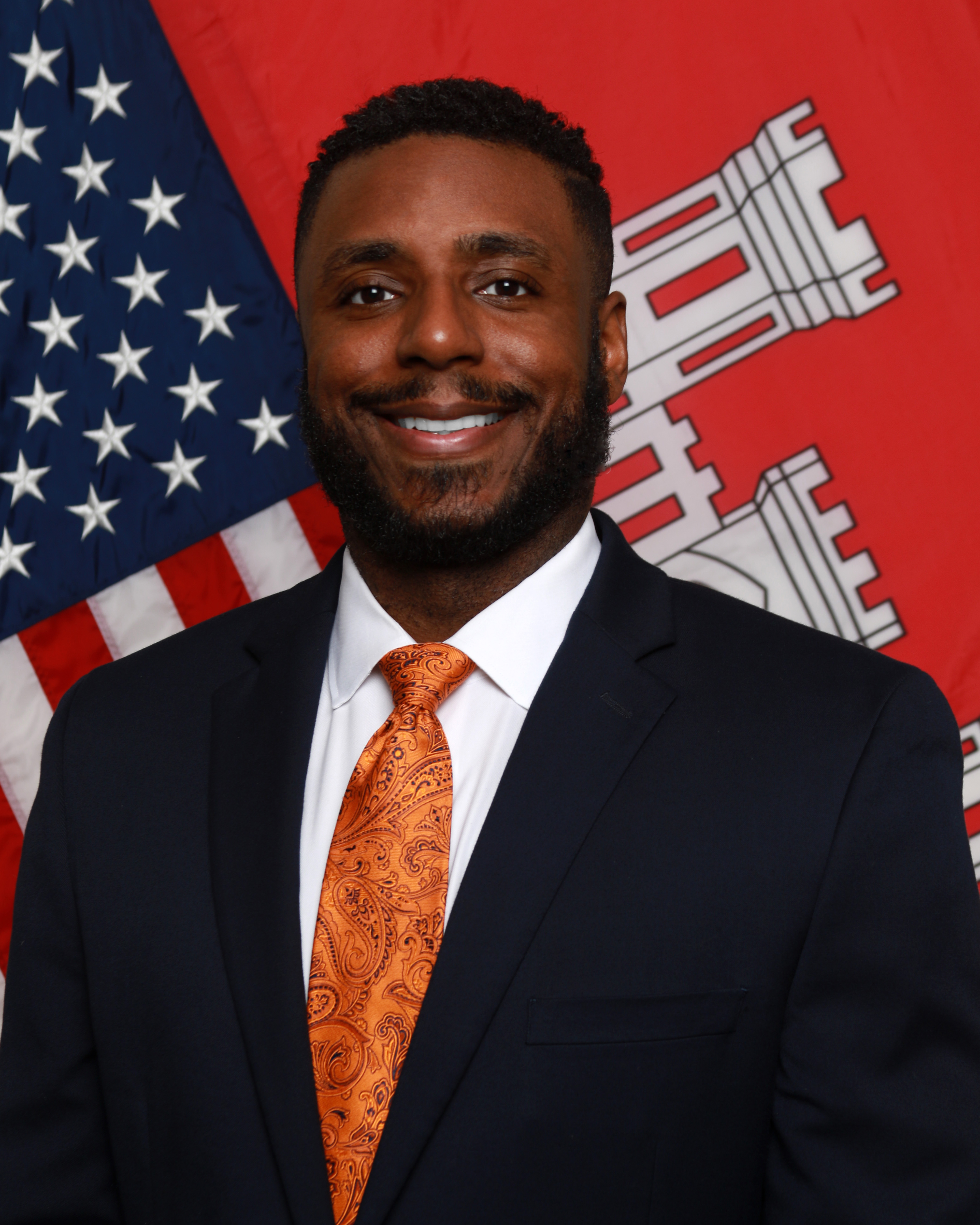 Durund Elzey, wearing a dark blue suit with a snappy orange tie, stands in front of the American and U.S. Army Corps of Engineers flags. Durund Elzey, wearing a dark blue suit with a snappy orange tie, stands in front of the American and U.S. Army Corps of Engineers flags.